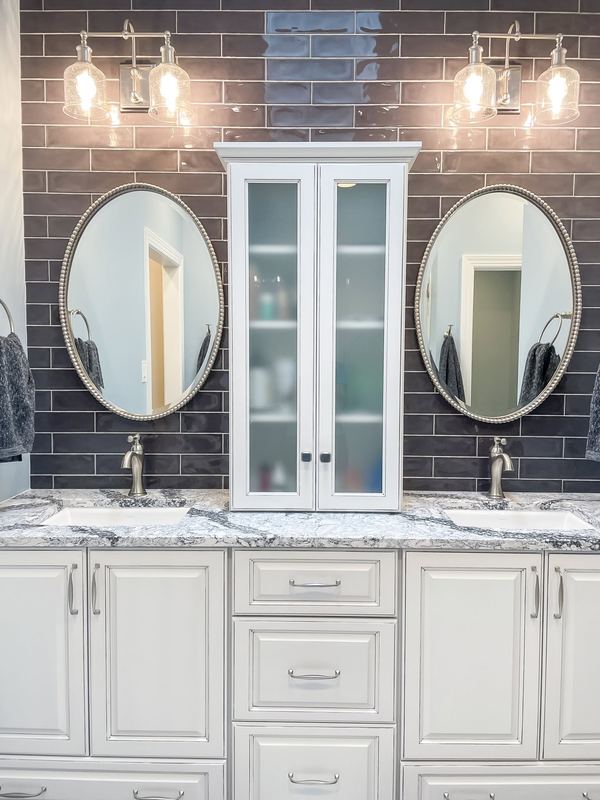 White cabinets and twin round mirrors, a bathroom remodel by Sidney Design & Build in Winchester, VA