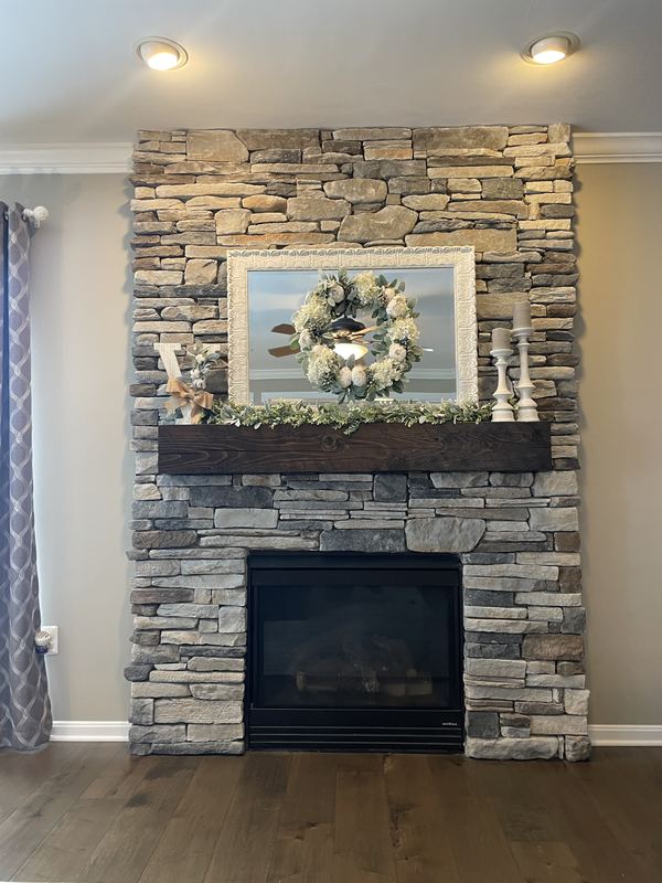 Stacked stone fireplace with a beam mantel, a fireplace renovation by Sidney Design & Build in Winchester, VA