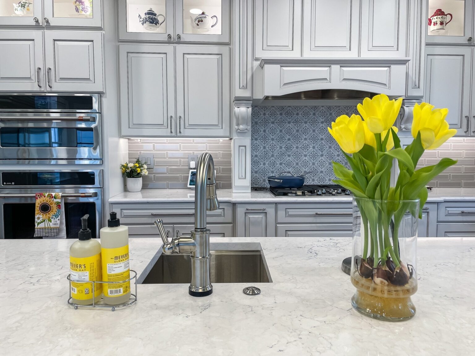 Kitchen remodel with stacked wall ovens, grey cabinets, quartz counters and a blue tile backsplash in Winchester, VA