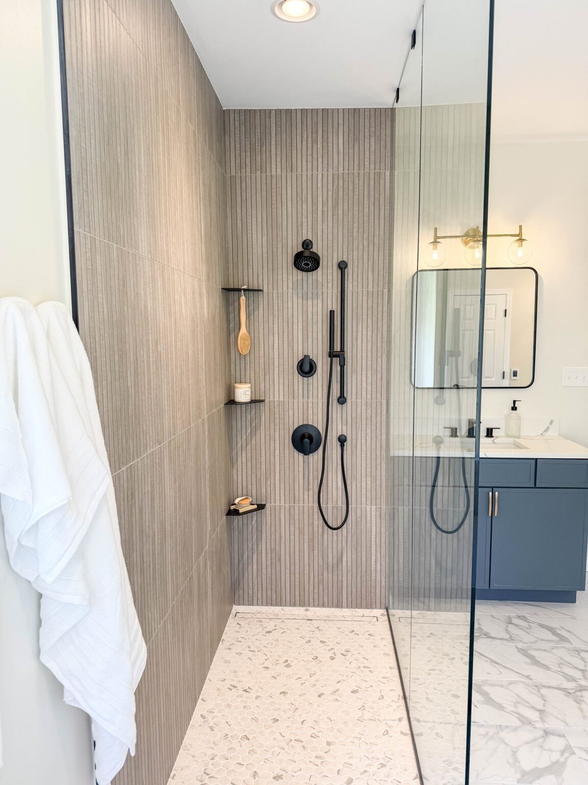 Walk in shower with a frameless glass panel, tiled niche and matte black handheld shower in Winchester, VA
