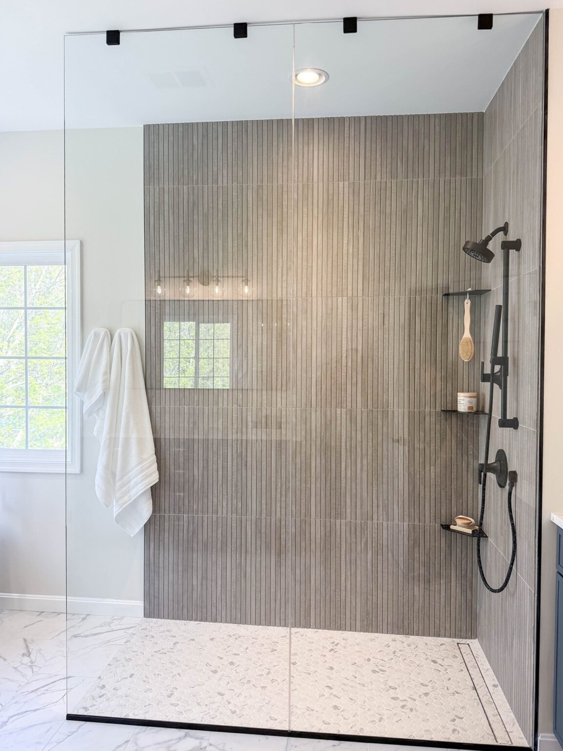 Walk in shower with a low threshold, linear wall tile, a glass panel and black fixtures, bathroom remodel in Winchester, VA